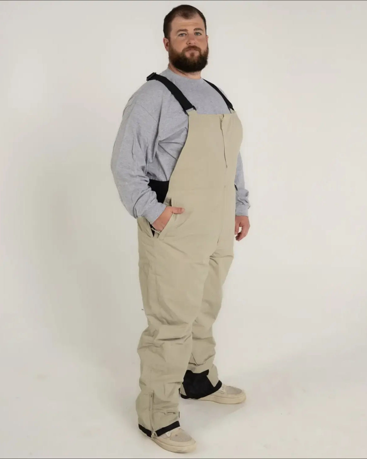 Man wearing tan Snow Country Outerwear skiing bib overalls in a product image
