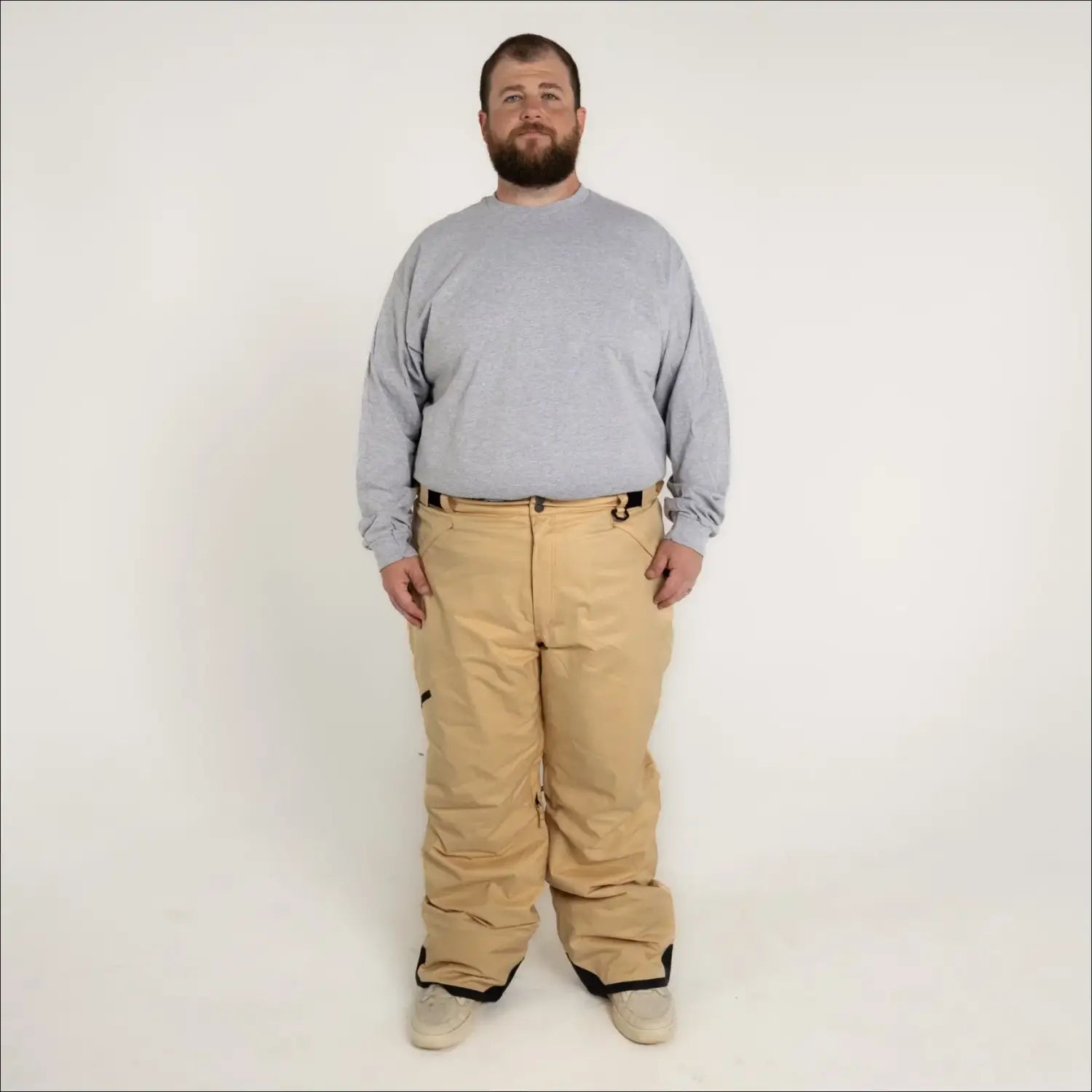 Man wearing tan Snow Country insulated winter ski snow pants and gray long-sleeve shirt