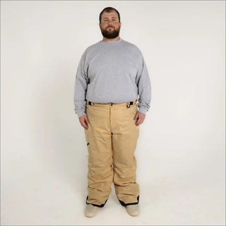 Man wearing tan Snow Country insulated winter ski snow pants and gray long-sleeve shirt