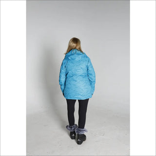 Woman in a blue winter coat, black leggings, and snow boots for Snow Country Outerwear Ski Coat