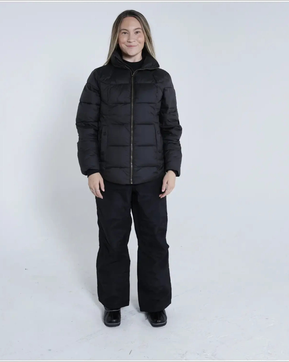 Woman in black puffer jacket and pants wearing Snow Country Outerwear Lexington Puffy Jacket