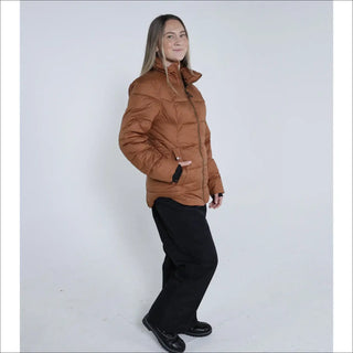 Woman wearing a brown puffer jacket and black pants in Snow Country Outerwear Lexington Puffy Jacket