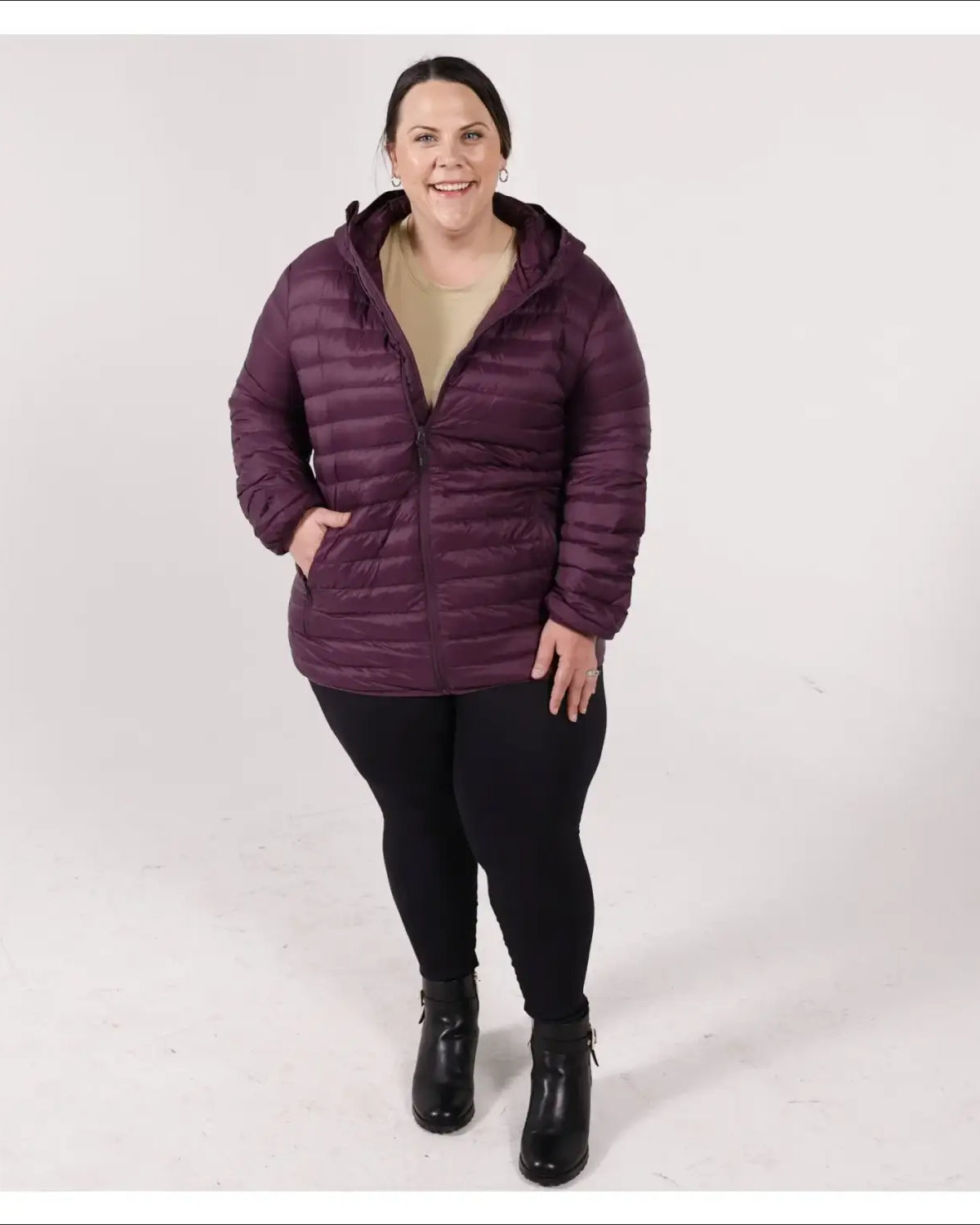 Woman in a hooded purple puffer jacket wearing Snow Country Outerwear’s packable down coat