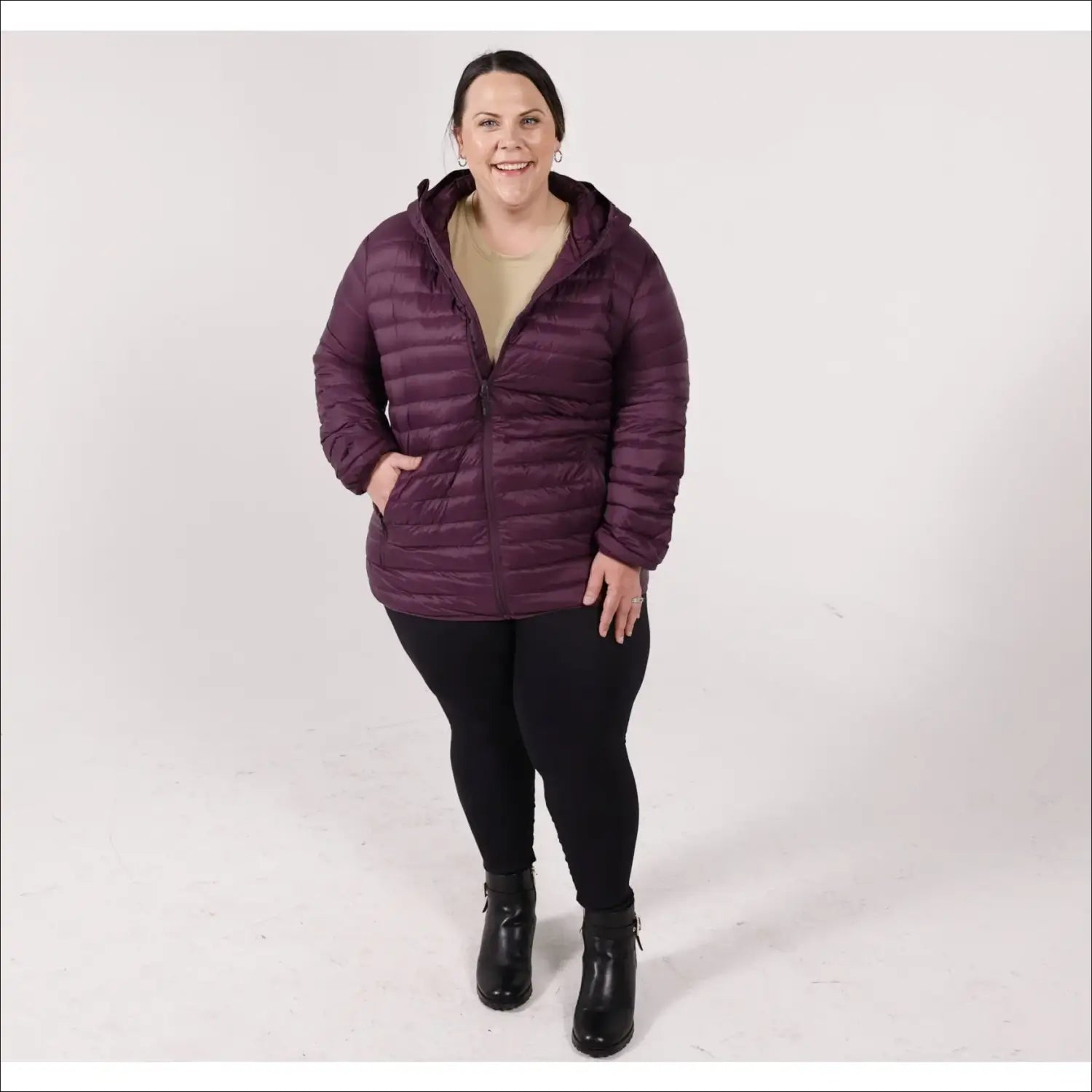 Woman in a hooded purple puffer jacket wearing Snow Country Outerwear’s packable down coat