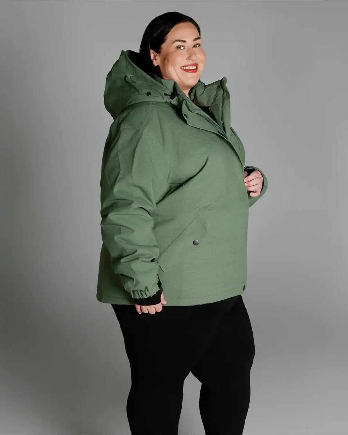 Woman wearing a green hooded winter coat from Snow Country Outerwear Plus Size collection