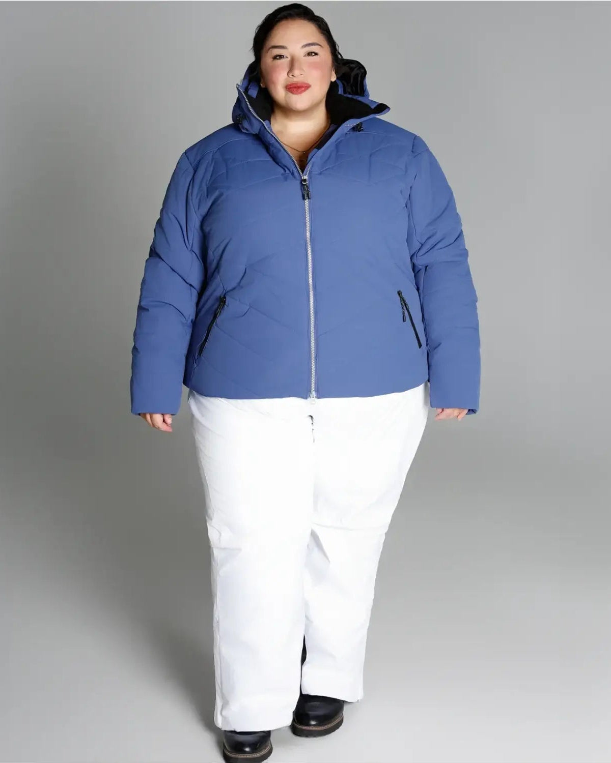 Woman in blue puffer jacket and white pants wearing Snow Country Outerwear Womens Plus Size Vail Ski Coat