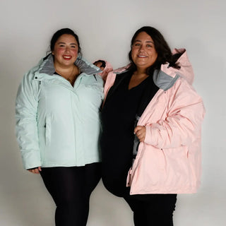 Two women wearing oversized insulated snow board jackets for winter skiing or snowboarding