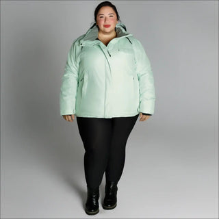 Woman wearing a light green plus size insulated snow board ski coat in winter outdoor setting