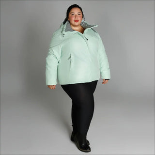 Woman wearing a light green plus size insulated snowboard ski coat in winter outdoor setting