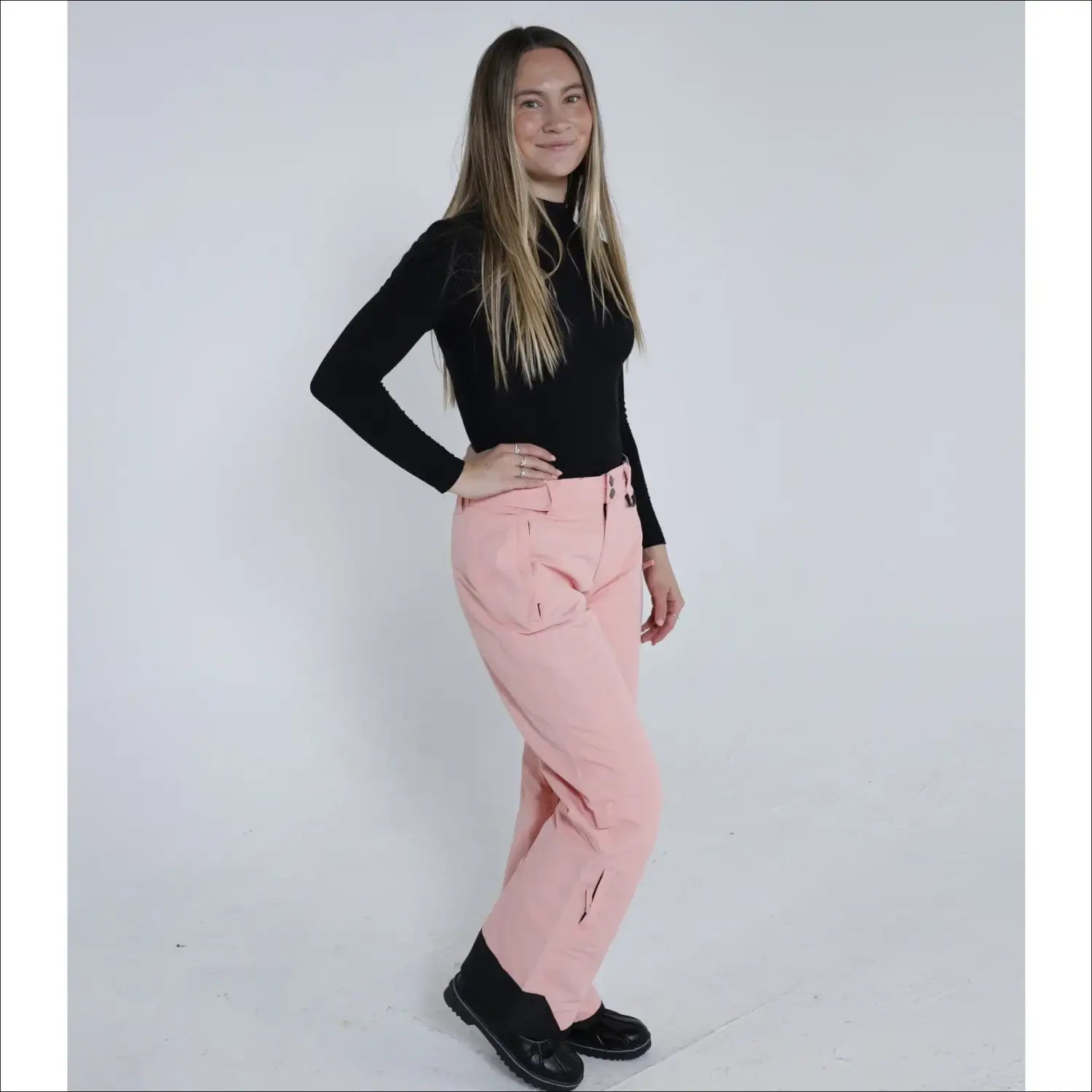 Woman in black top and pink ski pants wearing Snow Country Outerwear Women’s Ski Pants