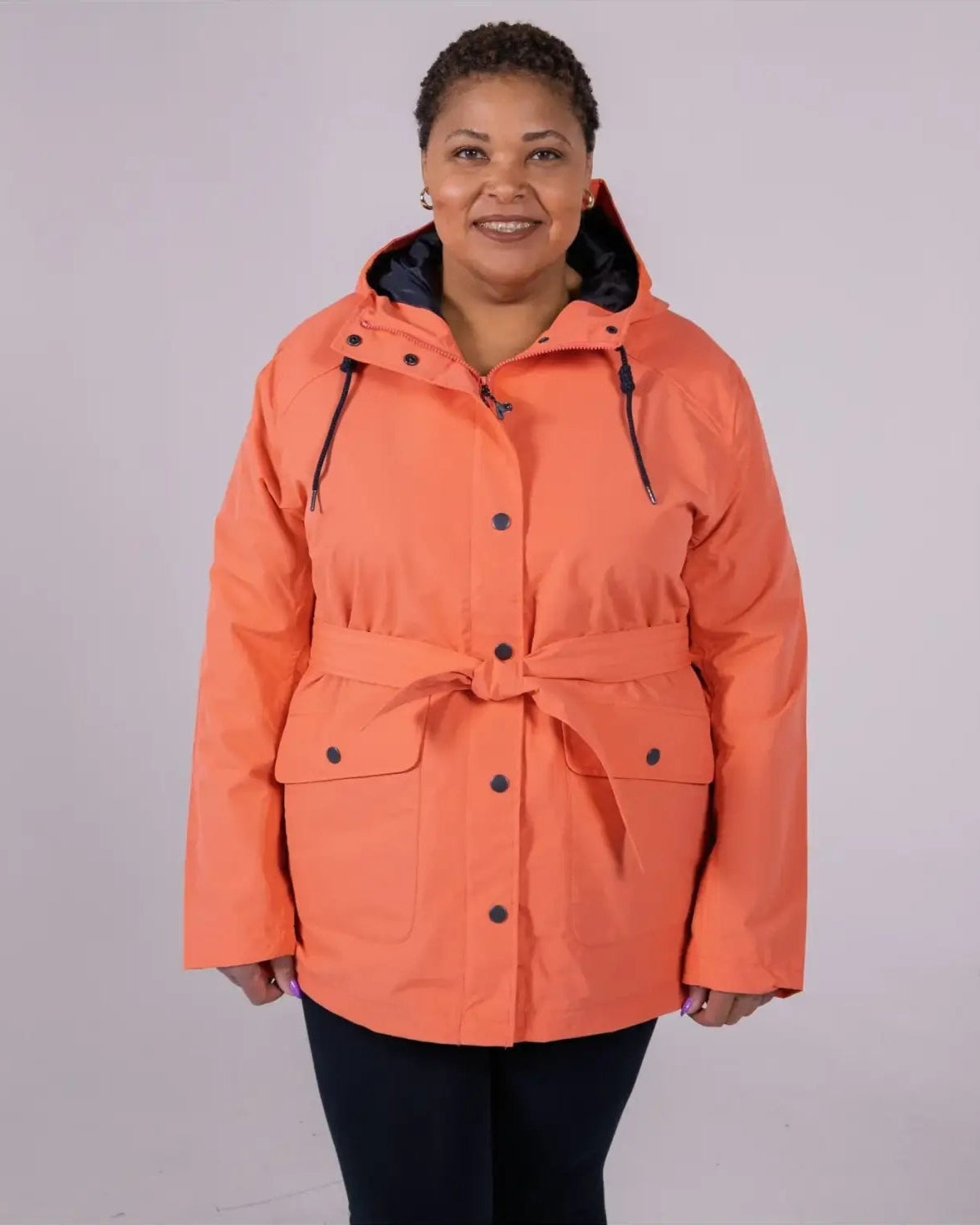 Woman wearing an orange belted trench coat from Snow Country Outerwear Rain Jacket collection