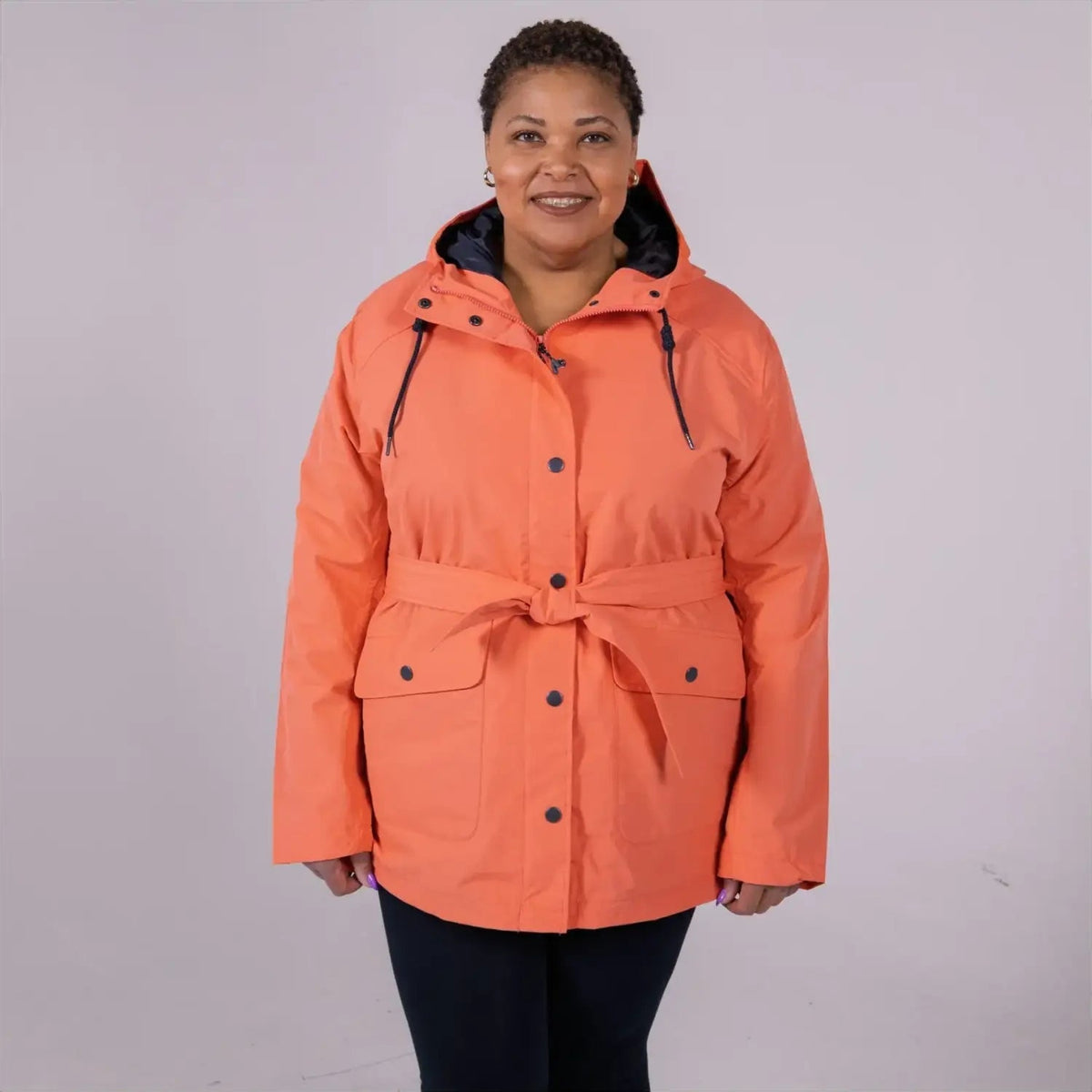 Woman wearing an orange belted trench coat from Snow Country Outerwear Rain Jacket collection