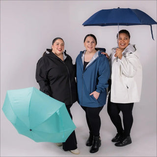 Three women in raincoats holding umbrellas showcasing Women’s Plus Size Waterproof Rain Jacket Camden