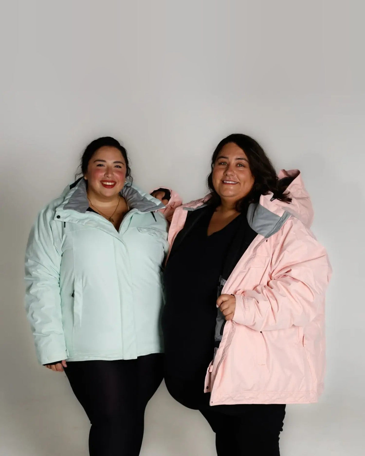 Two women wearing oversized insulated snow board jackets for winter skiing or snowboarding
