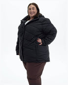 Black Geneva women's plus size mid length synthetic down jacket, three quarter view