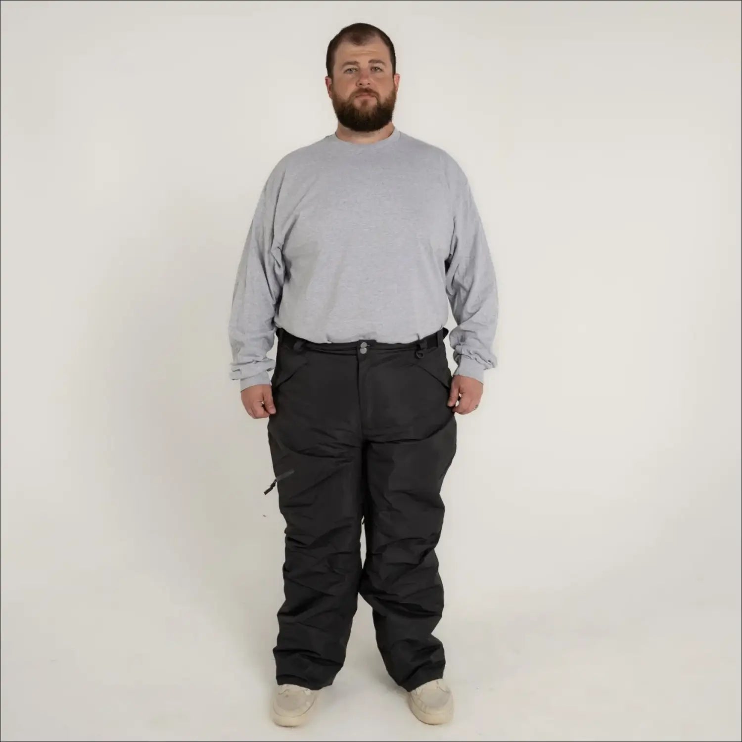 Man wearing gray long-sleeve shirt and black insulated snow pants for skiing