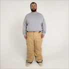 Man wearing tan Snow Country insulated winter ski snow pants and gray long-sleeve shirt