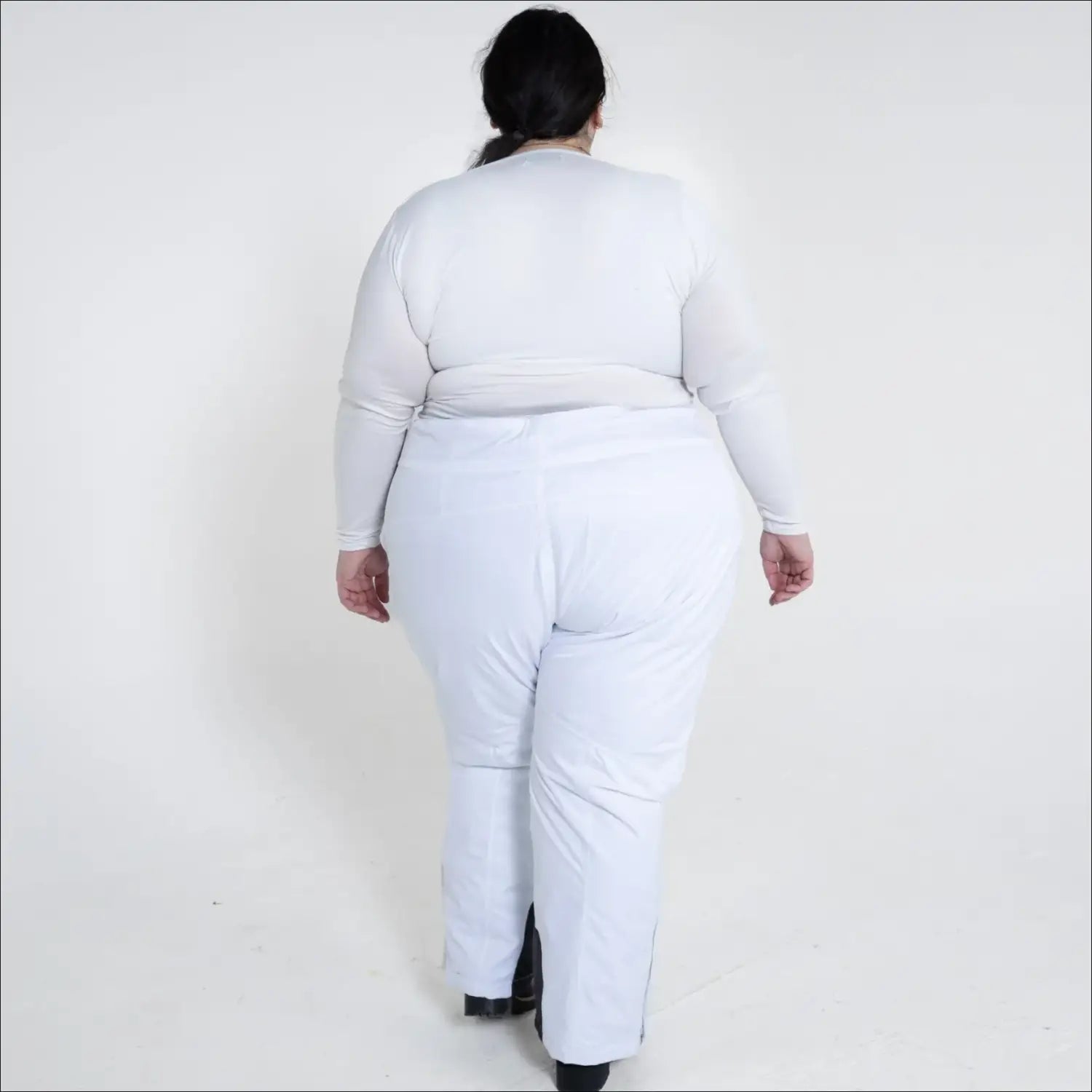 Woman in white winter skiing outfit wearing insulated snow ski pants outdoor scene