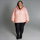 Woman wearing a pink puffer jacket from the Women’s Plus Extended Size Packable Down Coat collection