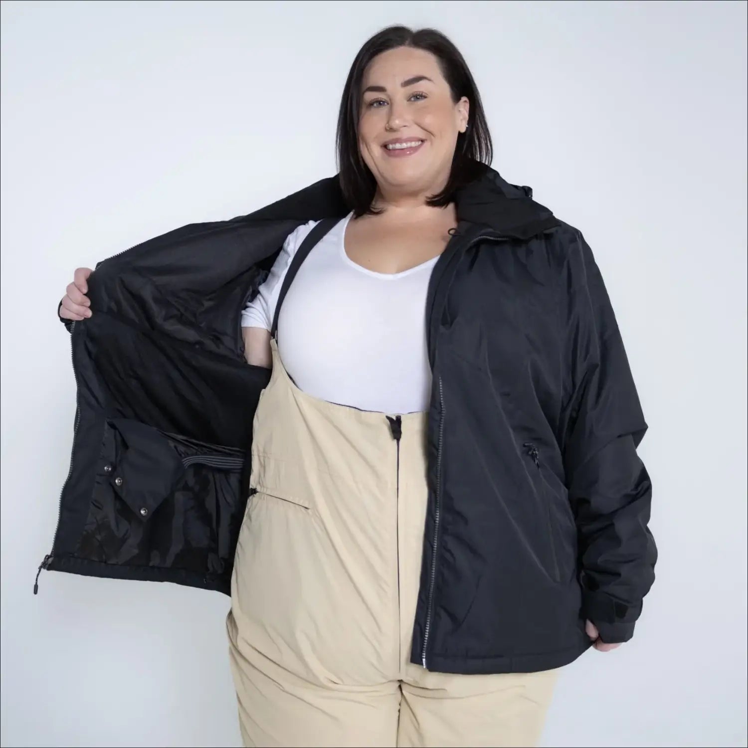 Woman in black jacket and beige overalls wearing Snow Country Plus Size Ski Jacket