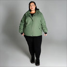 Woman wearing a green hooded jacket from Snow Country Outerwear Women’s Plus Size Fortress Ski Coat