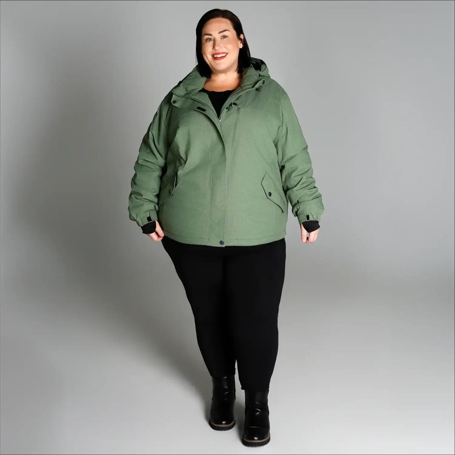 Woman wearing a green hooded jacket from Snow Country Outerwear Women’s Plus Size Fortress Ski Coat