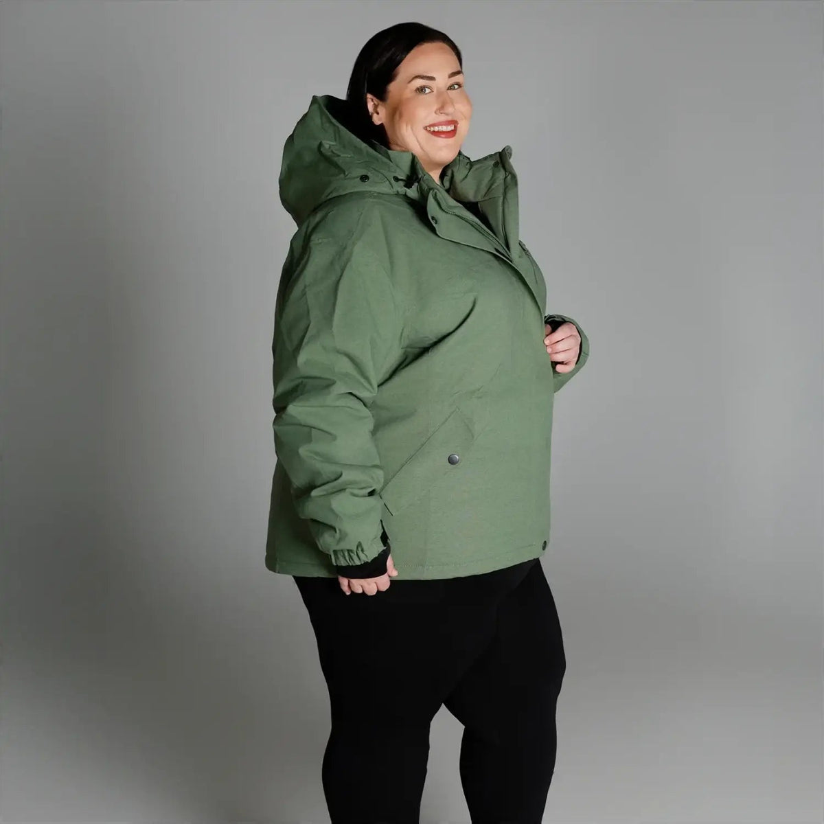 Woman wearing a green hooded winter coat from Snow Country Outerwear Plus Size collection