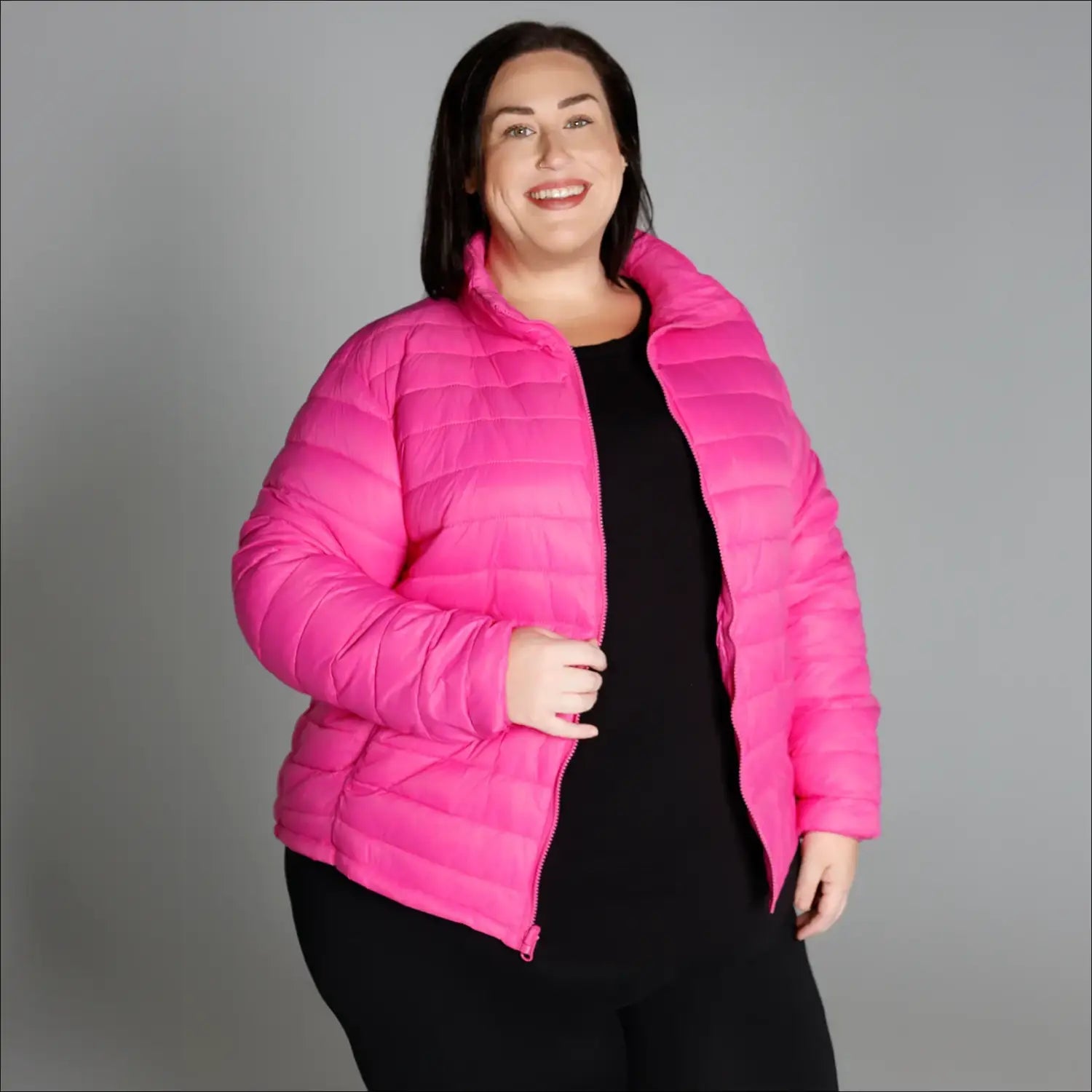 Woman wearing a bright pink plus size winter down alternative 3-in-1 coat jacket in snow country