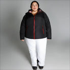 Woman wearing black and red winter jacket with white pants in Alps snow country outerwear scene