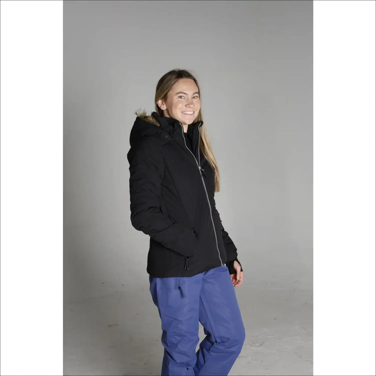 Woman in black winter jacket and blue pants wearing Snow Country Outerwear Ski Coat