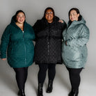 Three plus-size women wearing stylish quilted puffer coats from Savvy Transitional collection