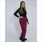 Woman wearing black turtleneck and burgundy Snow Country ski pants for women snowboarding