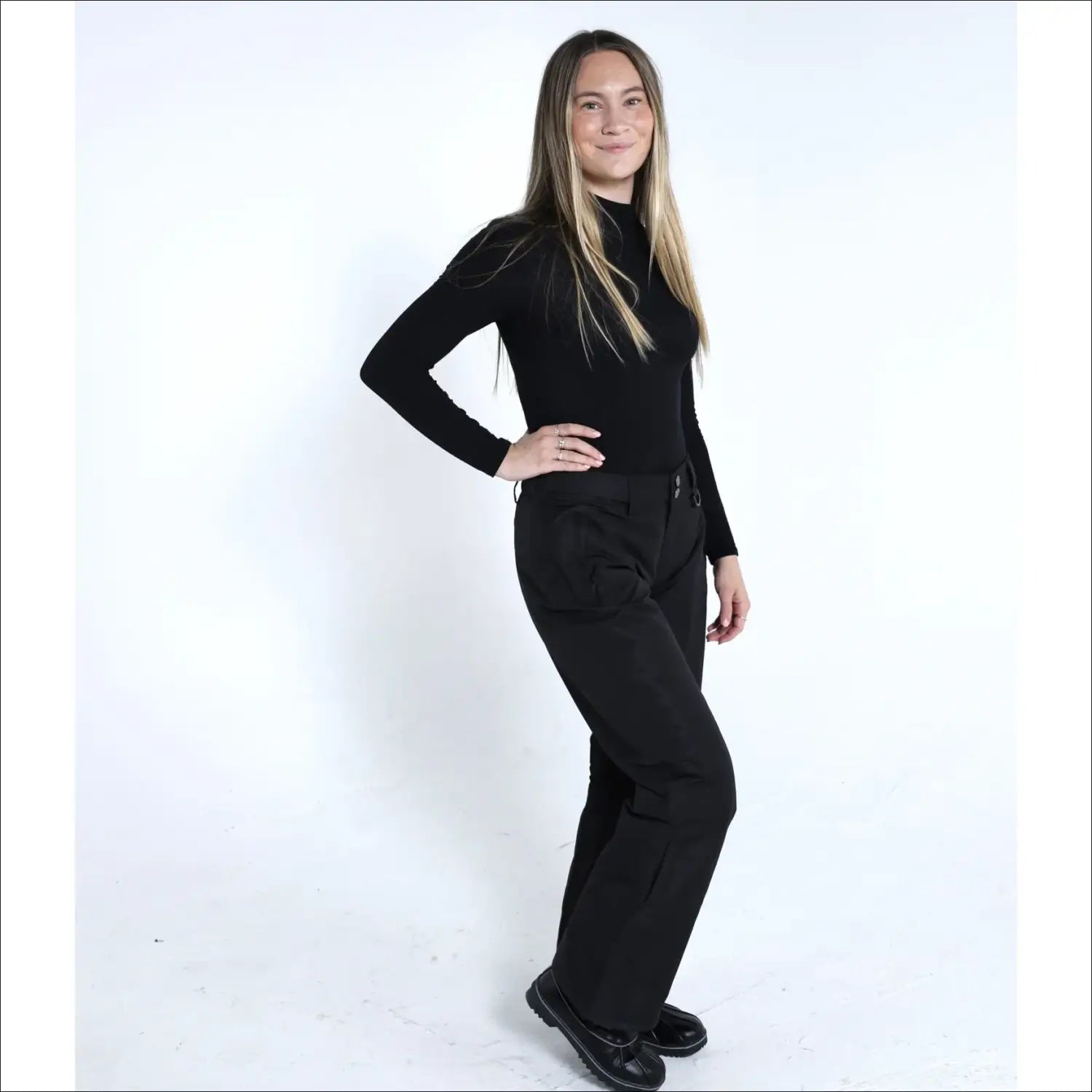 Woman in black turtleneck and pants wearing Snow Country Women’s Ski Pants for snowboarding