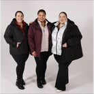 Three women wearing plus size winter coats in snowy outdoor setting
