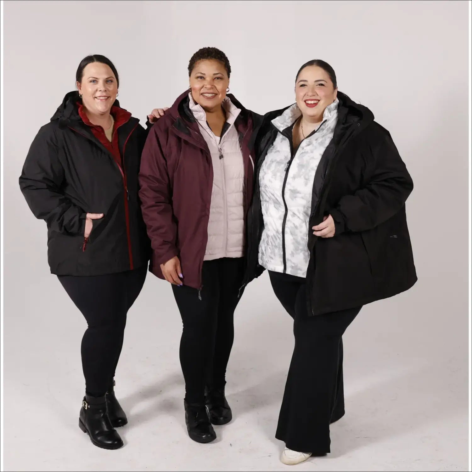 Three women wearing plus size winter coats in snowy outdoor setting