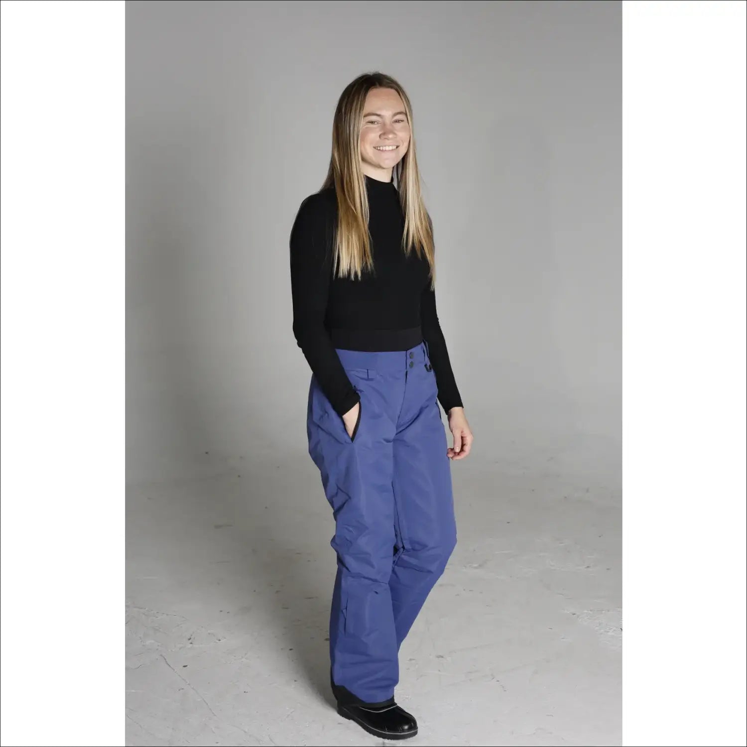 Woman wearing blue Snow Country ski pants and black turtleneck for snowboarding