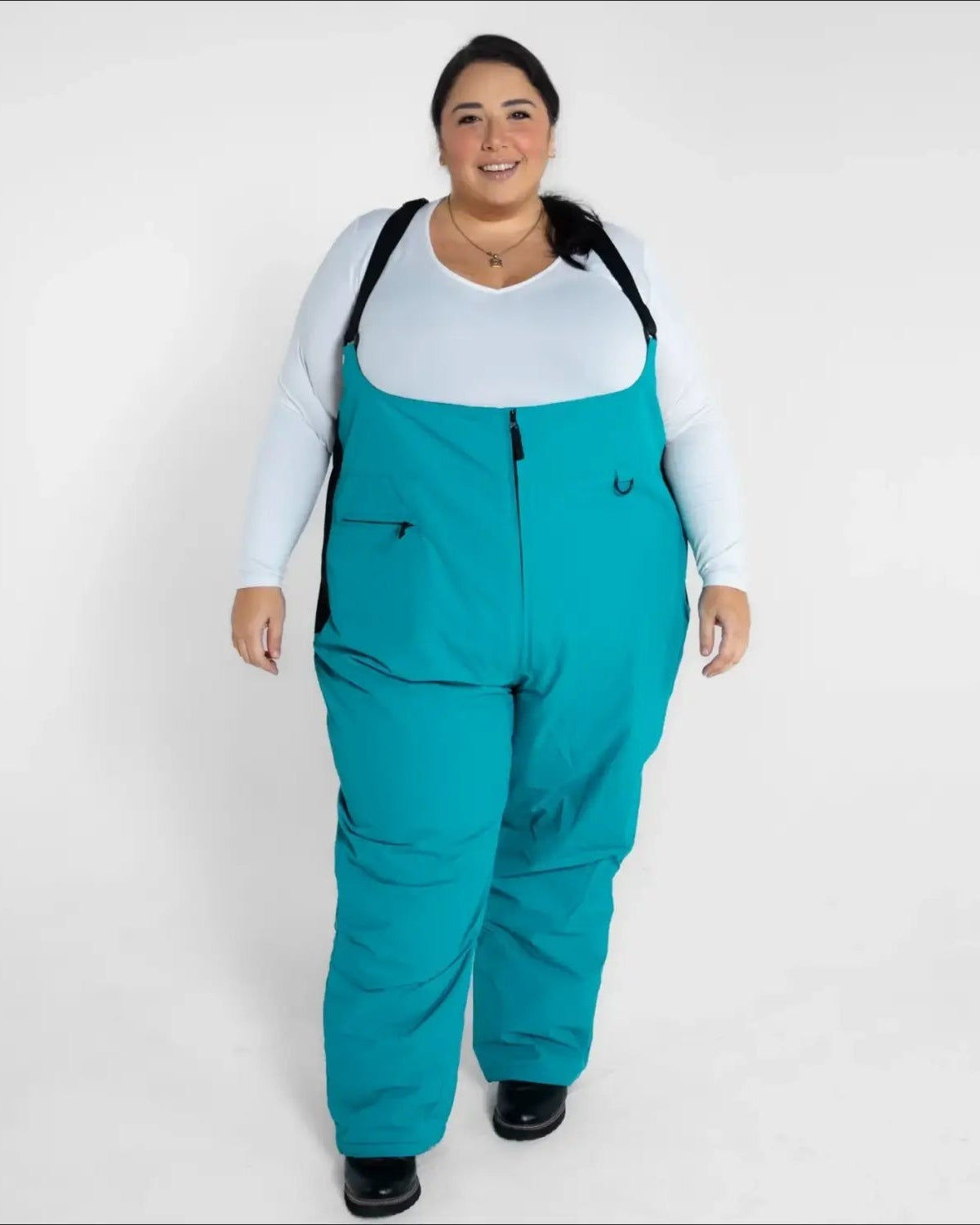 Woman wearing teal Snow Country Outerwear plus size Vertex winter snow ski bibs
